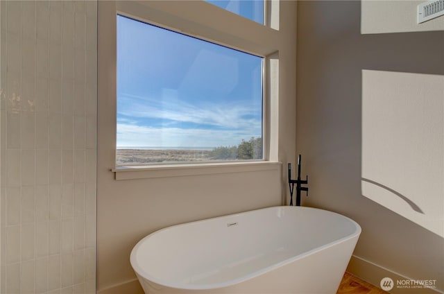 full bathroom with a freestanding bath, visible vents, and baseboards