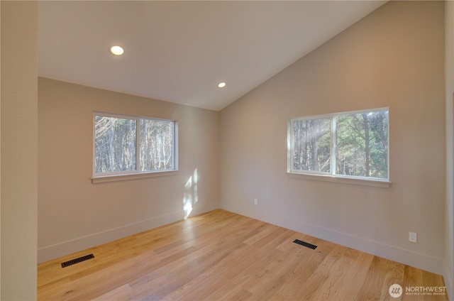 unfurnished room with lofted ceiling, a wealth of natural light, and visible vents