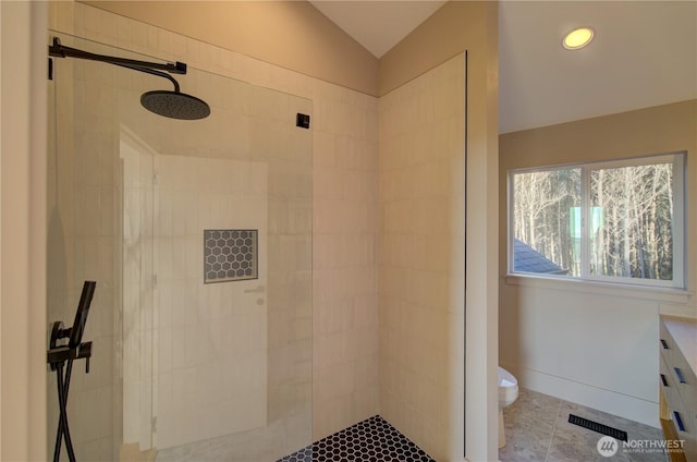 bathroom featuring toilet, visible vents, baseboards, a tile shower, and tile patterned floors