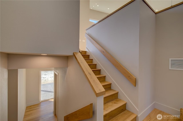 staircase with visible vents, baseboards, and wood finished floors