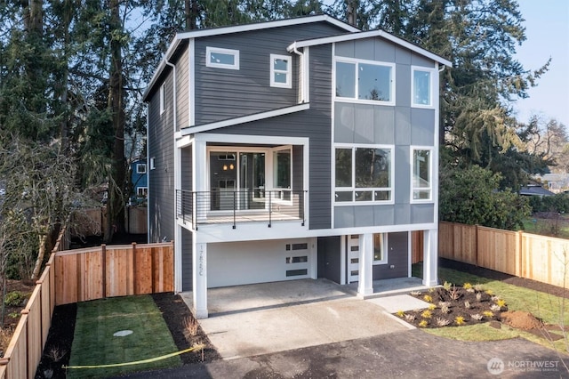 view of front facade featuring an attached garage, a balcony, fence, and concrete driveway