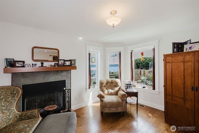 living area with a fireplace, wood finished floors, and baseboards