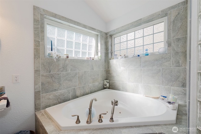 bathroom with vaulted ceiling and a tub with jets