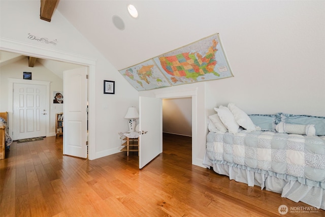 bedroom with light wood-type flooring, vaulted ceiling with beams, and baseboards