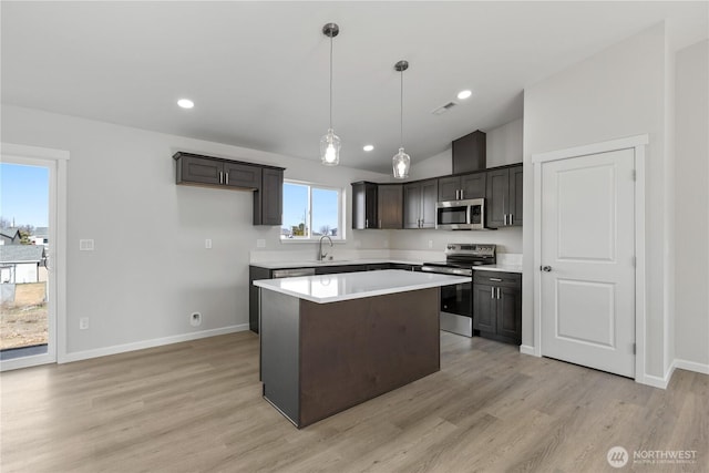 kitchen featuring light wood finished floors, a kitchen island, appliances with stainless steel finishes, light countertops, and a sink