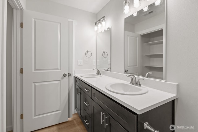 bathroom with double vanity, visible vents, a sink, and wood finished floors