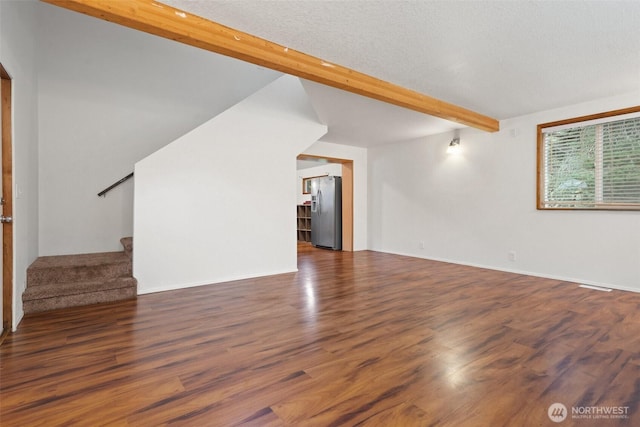 unfurnished living room with beamed ceiling, stairway, and wood finished floors