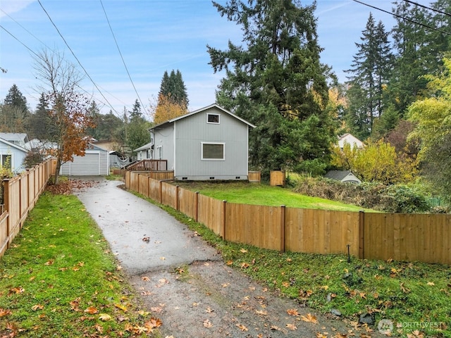 view of home's exterior with a yard, crawl space, an outdoor structure, and fence private yard