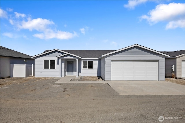 ranch-style house featuring a garage, driveway, a shingled roof, and fence