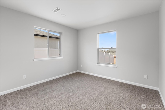 carpeted empty room featuring plenty of natural light, visible vents, and baseboards