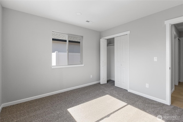 unfurnished bedroom with a closet, carpet flooring, visible vents, and baseboards