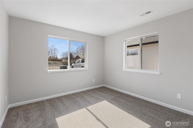 empty room featuring carpet floors, visible vents, and baseboards