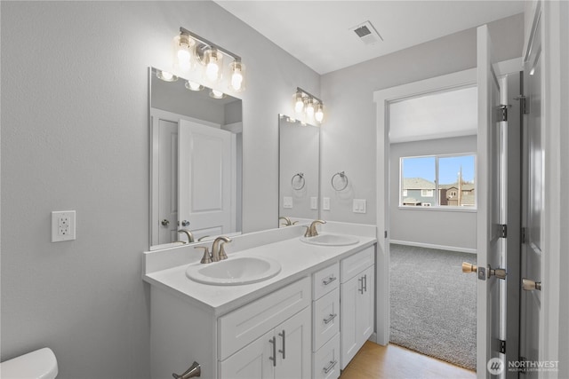 full bathroom with visible vents, a sink, toilet, and double vanity