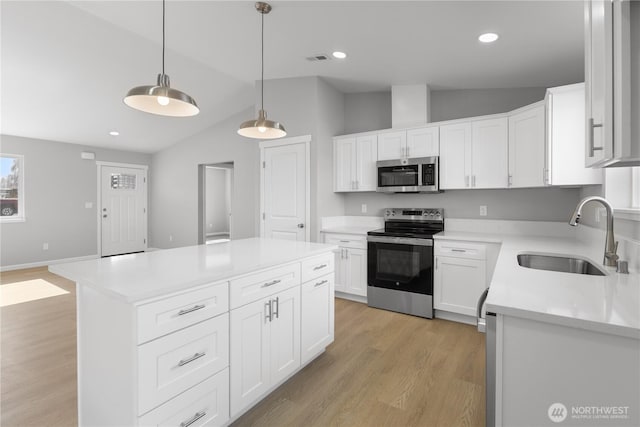 kitchen featuring light wood finished floors, stainless steel appliances, lofted ceiling, light countertops, and a sink