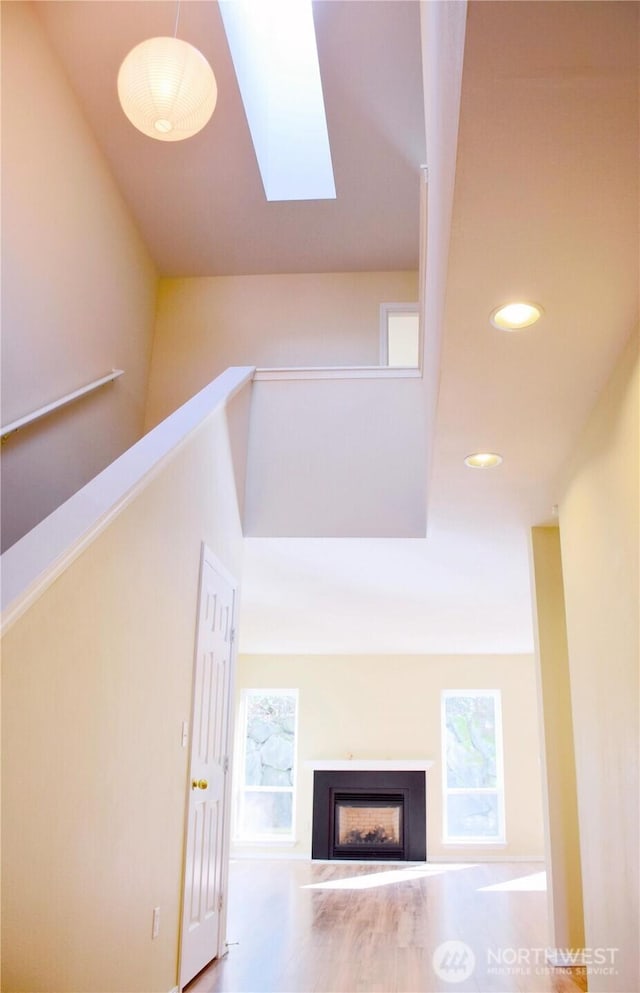 interior space featuring lofted ceiling with skylight, recessed lighting, a fireplace, and wood finished floors