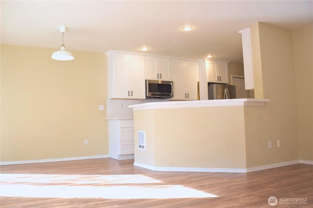 kitchen with visible vents, white cabinetry, stainless steel appliances, and light wood-type flooring