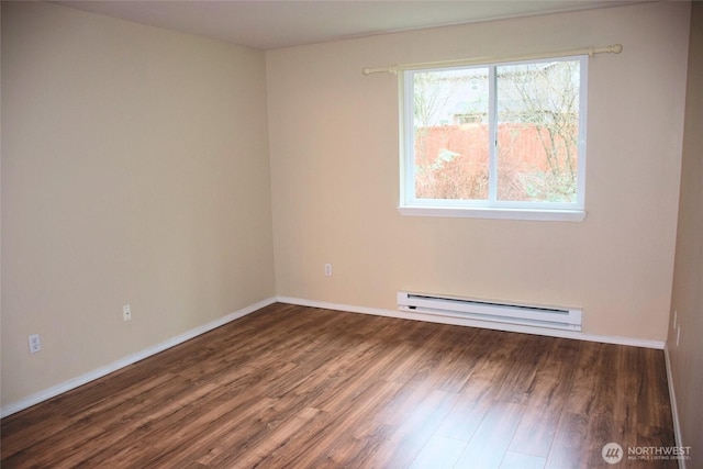 spare room with a baseboard heating unit, baseboards, and wood finished floors