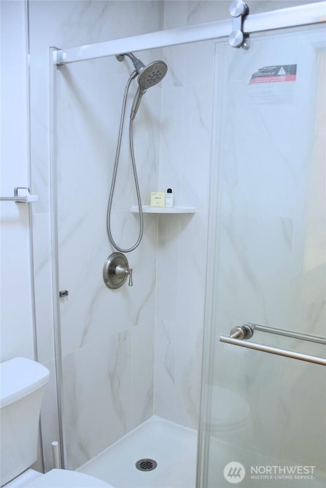 full bath featuring a shower stall and toilet