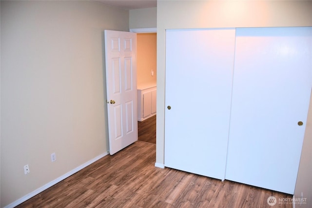 unfurnished bedroom with a closet, baseboards, and wood finished floors