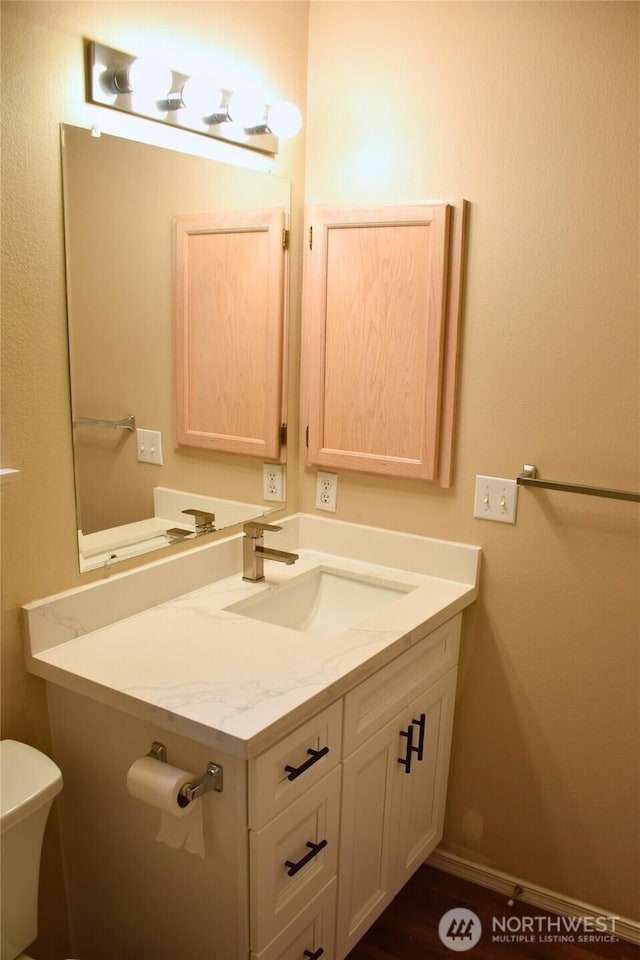 bathroom featuring toilet, vanity, and baseboards