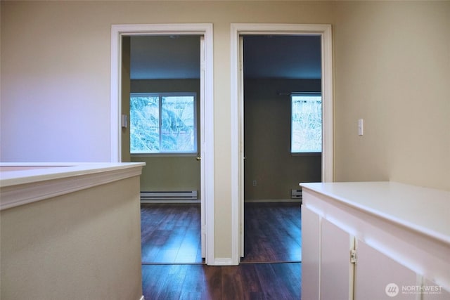 corridor featuring dark wood-type flooring, baseboards, and a baseboard radiator