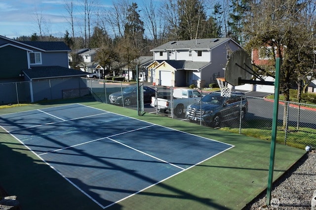 view of tennis court with a residential view and fence