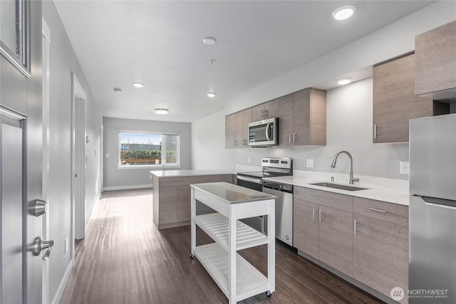 kitchen featuring baseboards, dark wood-style floors, appliances with stainless steel finishes, light countertops, and a sink