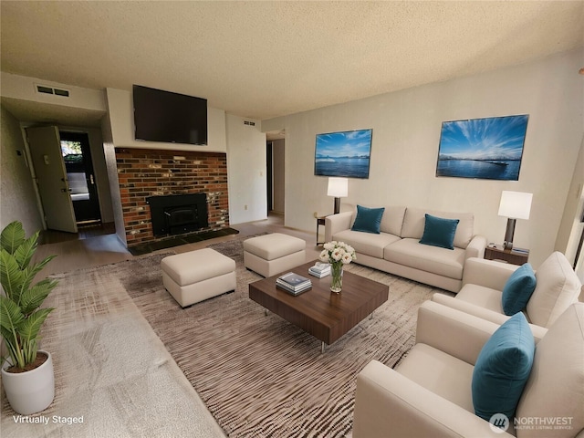 living area with a brick fireplace, visible vents, and a textured ceiling