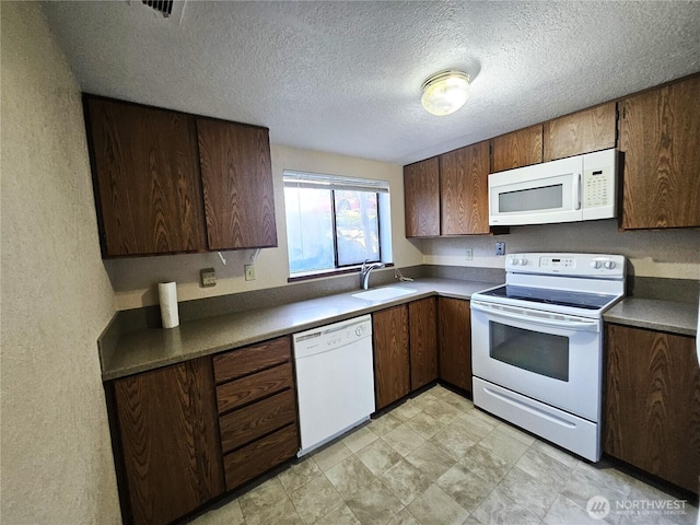 kitchen with a textured ceiling, white appliances, a sink, visible vents, and dark countertops