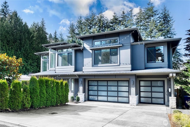 modern home with a garage, stone siding, and driveway