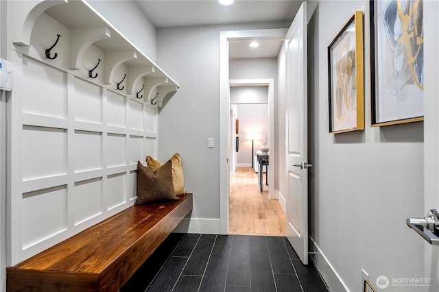 mudroom with dark wood finished floors and baseboards