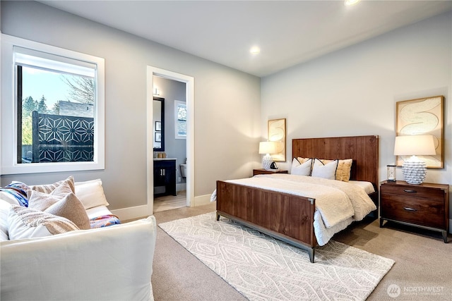 bedroom with baseboards, recessed lighting, ensuite bathroom, and light colored carpet