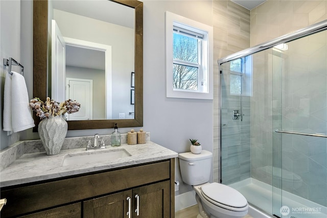 bathroom with a shower stall, toilet, and vanity