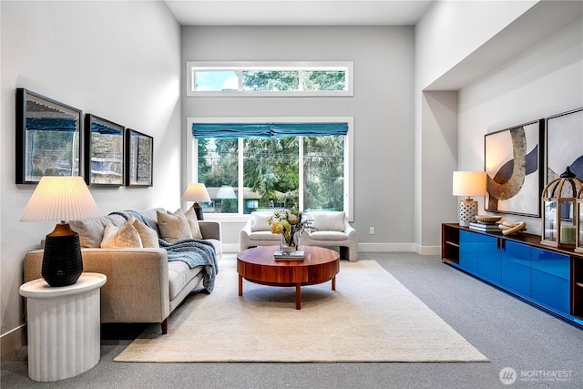 carpeted living area with a towering ceiling and baseboards