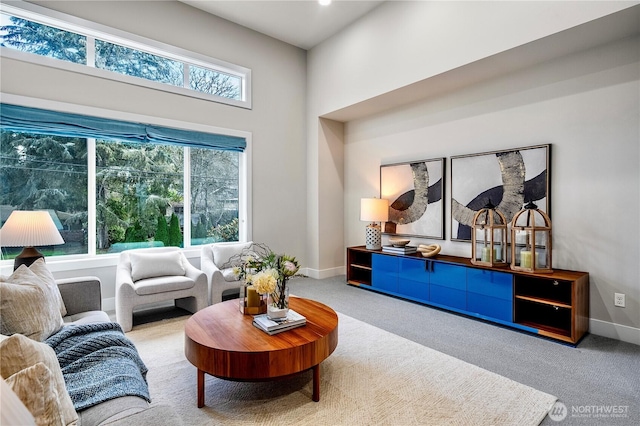 carpeted living room with a towering ceiling and baseboards