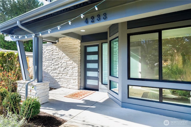 doorway to property featuring covered porch and stone siding