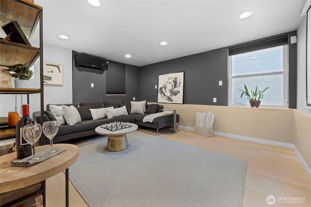 living area with an AC wall unit, wood finished floors, recessed lighting, and baseboards