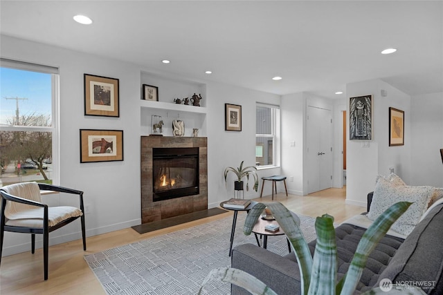 living area featuring recessed lighting, baseboards, light wood finished floors, and a tile fireplace