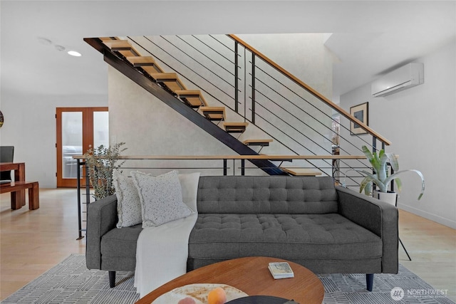 living area with a wall unit AC, stairway, baseboards, light wood-style floors, and french doors