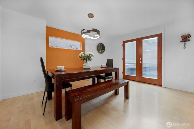 dining space featuring french doors, plenty of natural light, baseboards, and light wood-style flooring