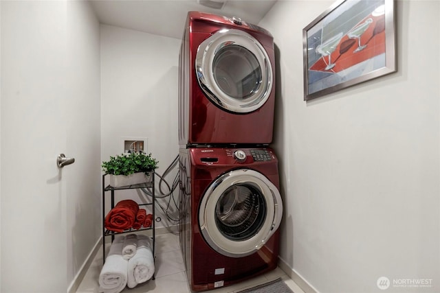 laundry area with tile patterned floors, baseboards, laundry area, and stacked washing maching and dryer