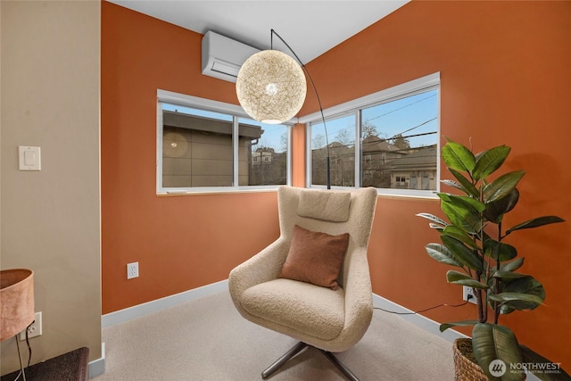 sitting room with an AC wall unit, carpet flooring, and baseboards