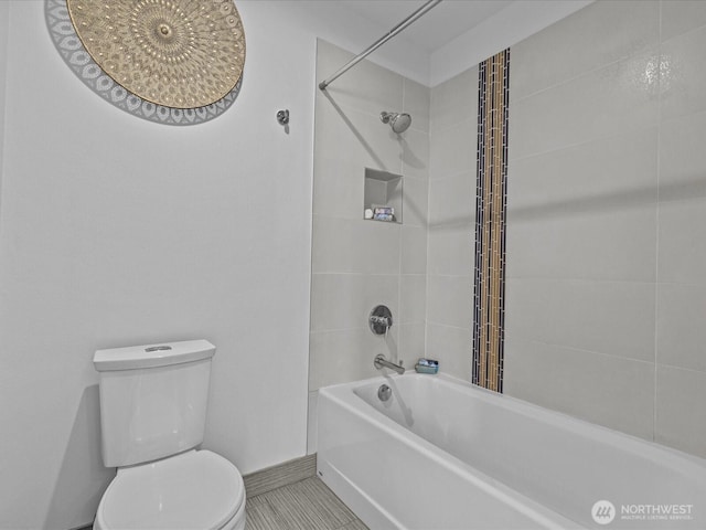 bathroom featuring bathtub / shower combination, toilet, and baseboards