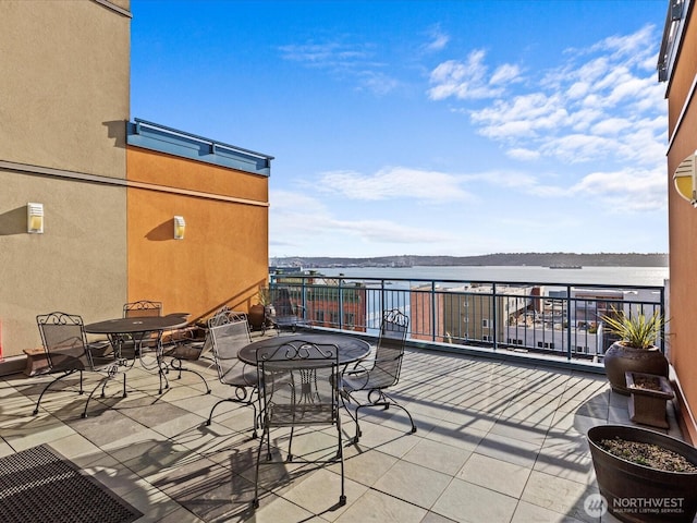 view of patio / terrace with a balcony, a water view, and outdoor dining space