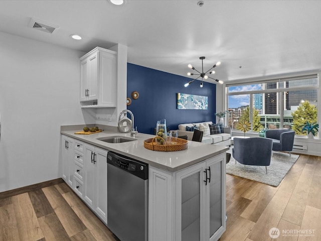 kitchen featuring a peninsula, wood finished floors, visible vents, open floor plan, and dishwasher