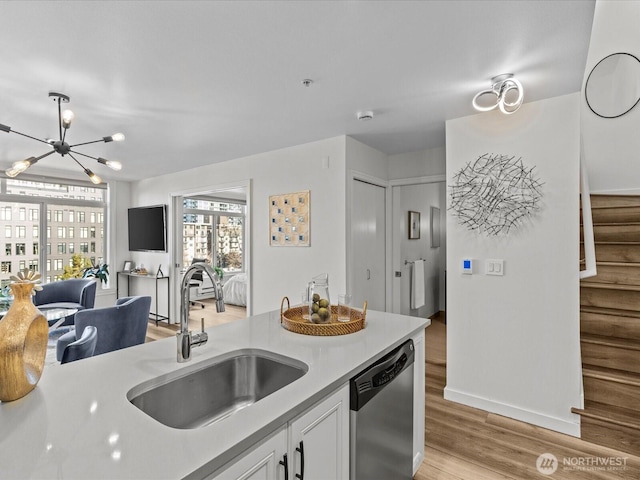 kitchen with white cabinets, dishwasher, light countertops, light wood-style floors, and a sink