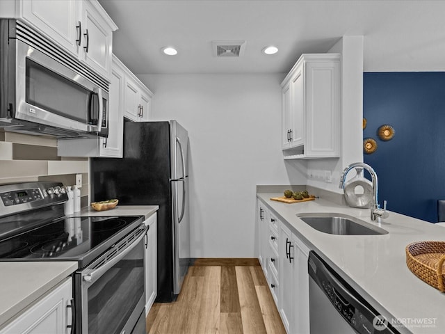 kitchen with visible vents, appliances with stainless steel finishes, light countertops, light wood-style floors, and a sink