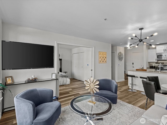 living room with baseboards, wood finished floors, and a notable chandelier