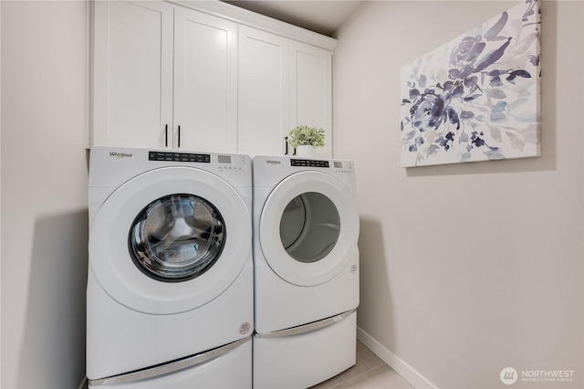 clothes washing area with cabinet space, washing machine and dryer, and baseboards