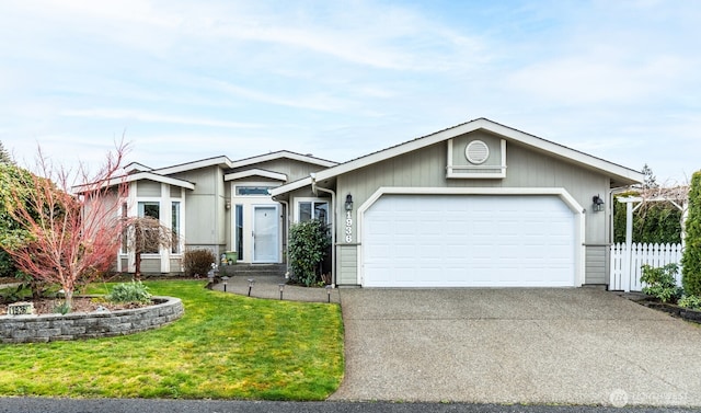 view of front facade with a front yard, concrete driveway, an attached garage, and fence